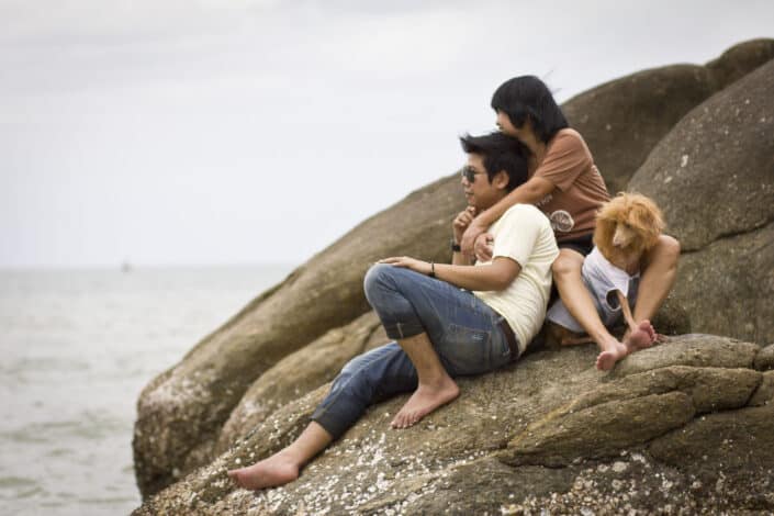 Couple sitting on rocks with dog beside them.