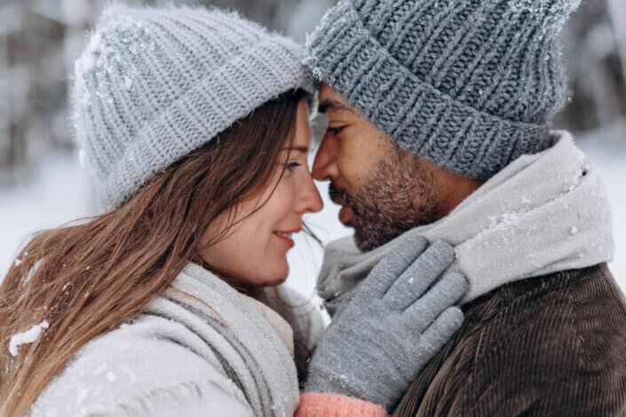 Couple about to kiss in snow.