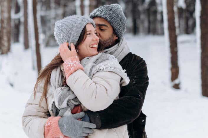 Guy embracing a girl in snow.