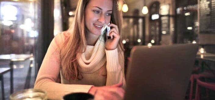 Woman talking to someone on her phone while working on her laptop