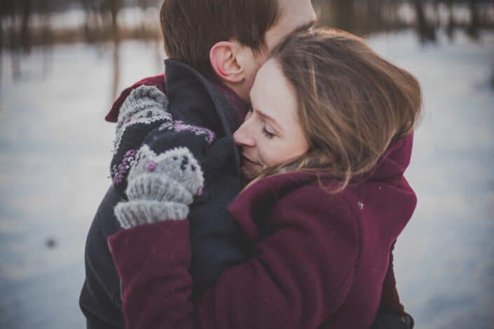 Couple hugging in the snow.