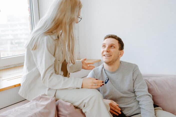 Couple smiling at each other on a sofa.