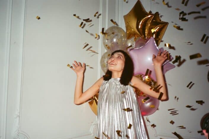 Girl celebrating with poppers and balloons.