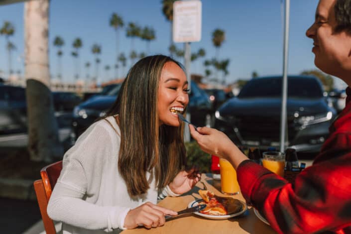 A woman trying out a bite offered by a man