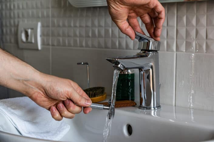 A man washing his shave under the faucet