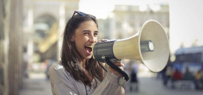 Cheerful woman speaking into megaphone