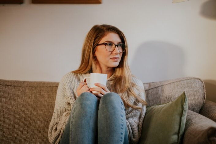 Girl drinking coffee on sofa.