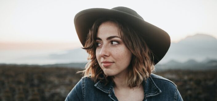 smiling woman wearing black hat and blue denim top