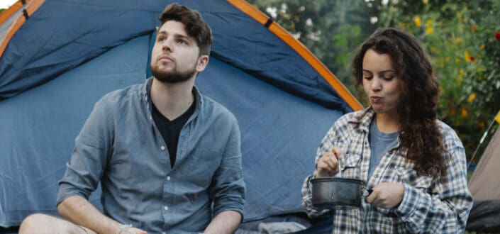 young couple eating at their camp