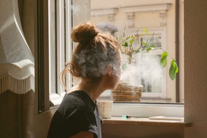 woman smoking while looking through the window