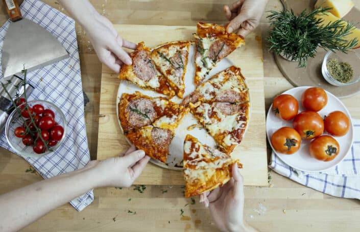 hands taking slices of the pizza