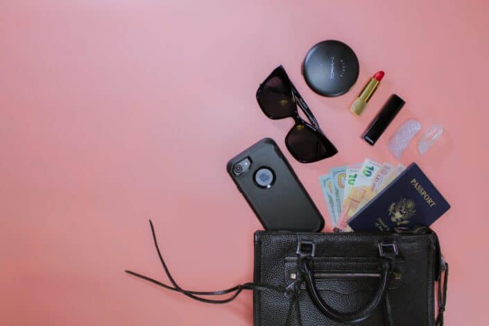 women essentials scattered from black leather pouch 