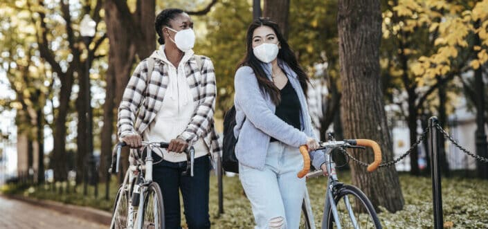 Diverse girlfriends with bike walking on a pavement