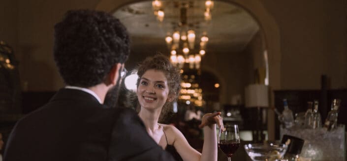 a woman happily having a drink with a bearded man
