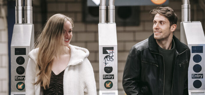 Happy couple walking through turnstile in underground