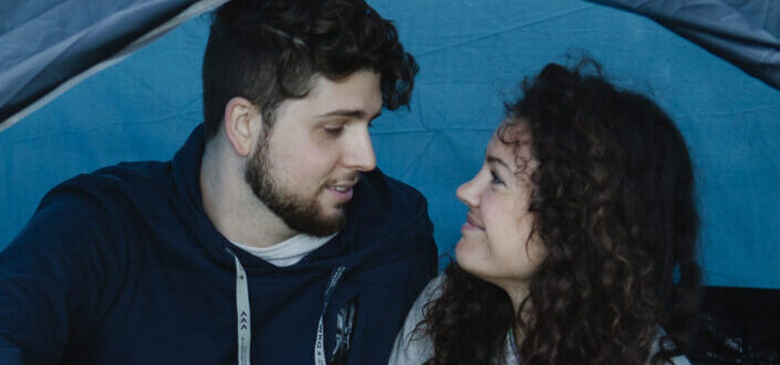 Loving young couple relaxing in tent during camping