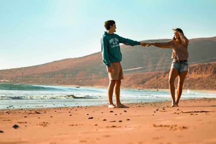 couple holding hands at seashore during daylight