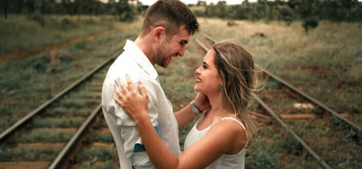 couple smiling between railroad tracks