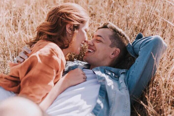 Smiling couple talking intimately on meadow in countryside