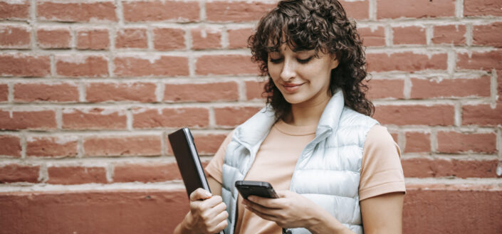 woman smiling at phone on street