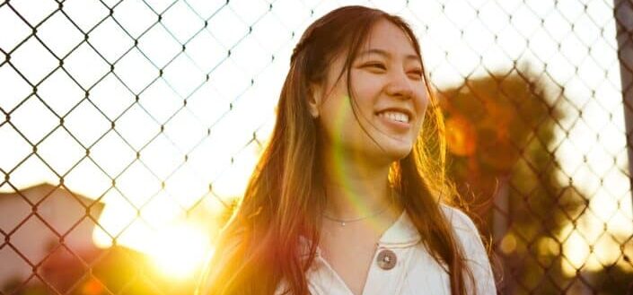 woman smiling on fence during golden hour