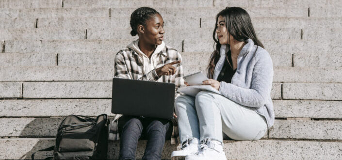 two diverse you woman talking to each other at a stair