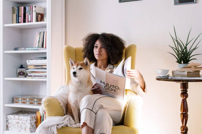 woman in a pajama sitting on a couch with her dog