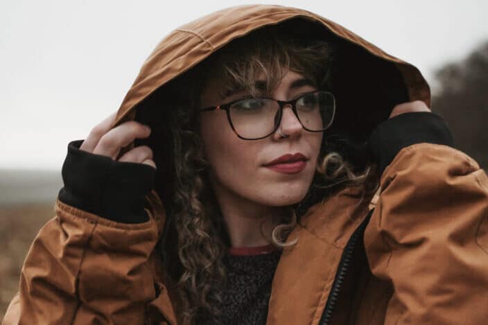 a woman in a brown jacket staring at something beside her