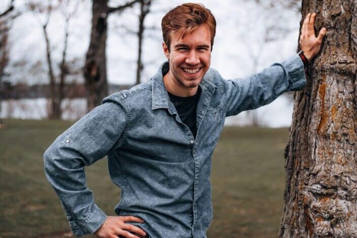 smiling man leaning at the tree