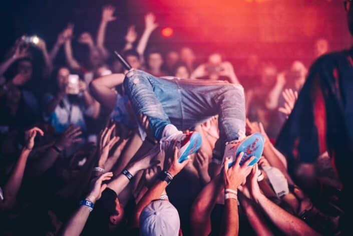 Man being lifted by people at a concert.