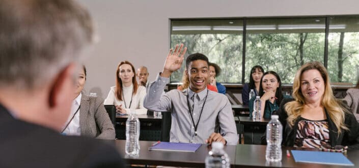 Man in a meeting raising his hand to ask a question.