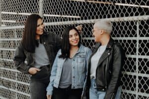 three friends talking to each other while smiling