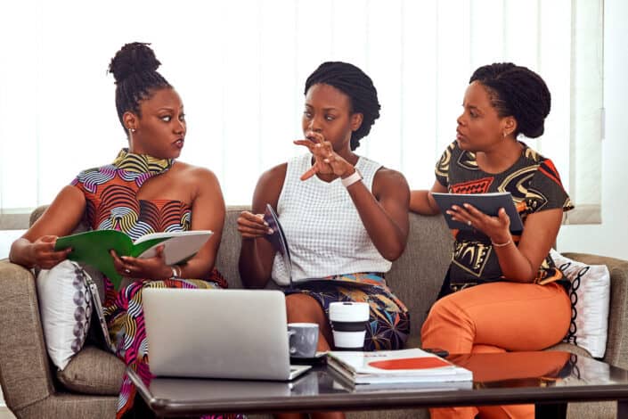 Three women discussing on a couch.