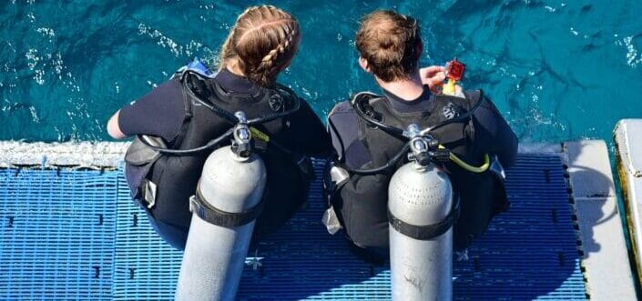 Two female scuba divers ready to dive into the water.