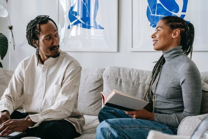 ethnic couple chatting while sitting on couch 