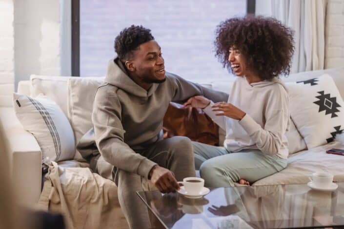 Happy black couple sharing news and smiling at table