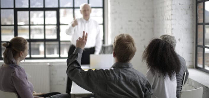 Man raising his hand to ask a question.