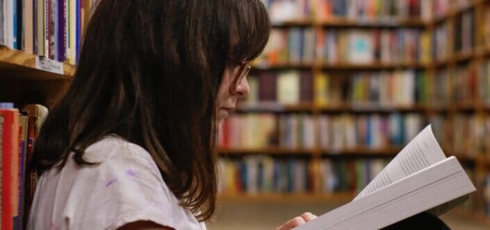Woman reading a book in a library.