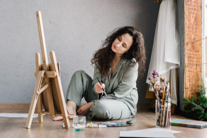 Woman sitting on the floor while painting.