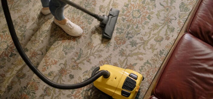 Person Holding Yellow and Black Vacuum Cleaner