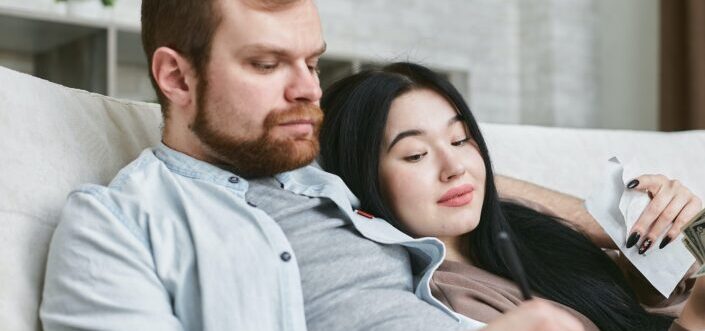 A woman taking a peek at her boyfriend's smartphone.