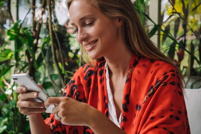 Woman in an orange robe smiling while looking at her phone
