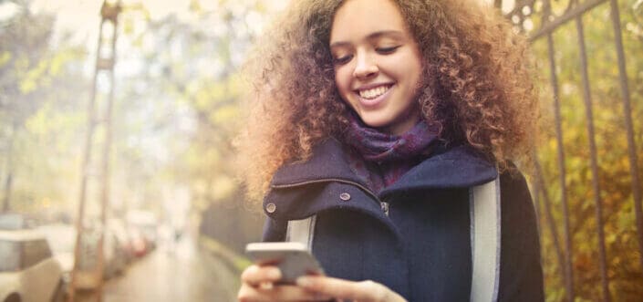 Curly blonde haired woman smiling on her phone