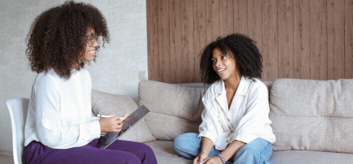 Two ladies talking about something while comfortably sitting in a couch
