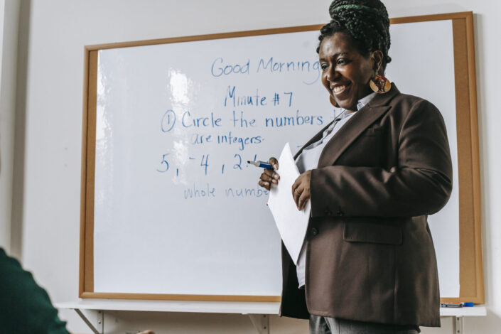 cheerful female teacher standing near whiteboard