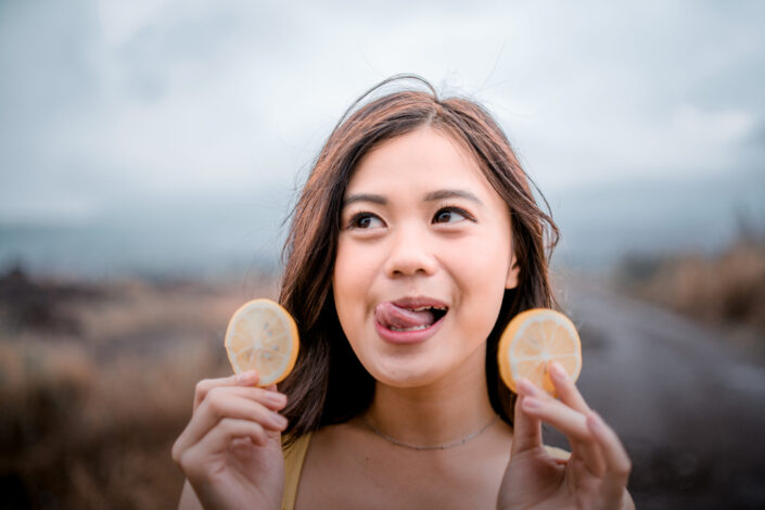 A girl holding two slices of oranges 