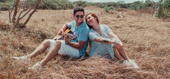 couple having guitar session in grassland