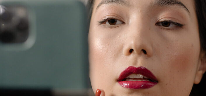Woman putting red maroon lipstick