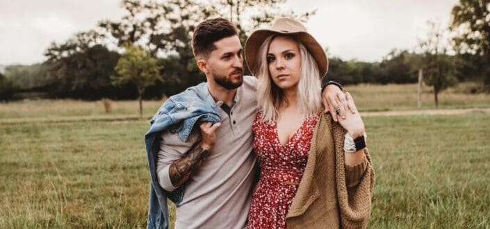 man holding woman while standing on grass area 