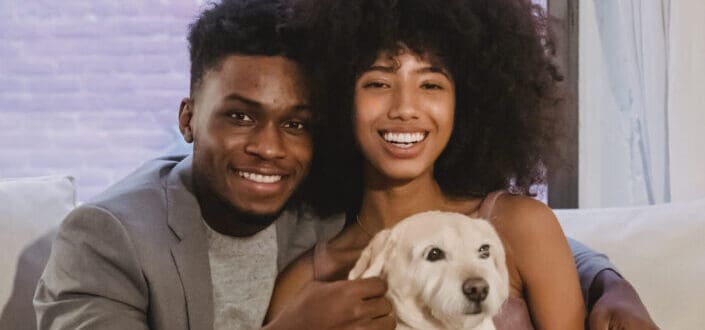 Lovely young couple sitting the couch with their dog 